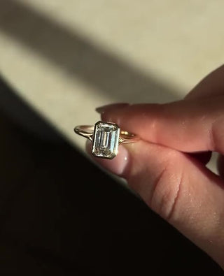 Emerald cut lab grown diamond bezel engagement ring in sleek white gold setting