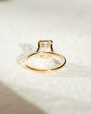 Emerald cut lab grown diamond bezel engagement ring in sleek white gold setting