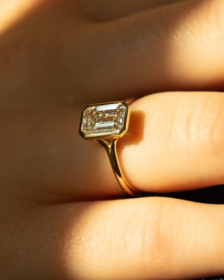 Emerald cut lab grown diamond bezel engagement ring in sleek white gold setting